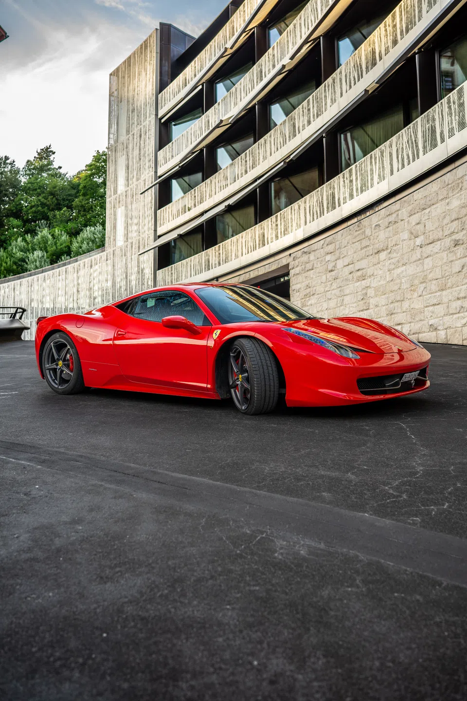 Ferrari 458 Italia neben einer modernen Hotelfassade