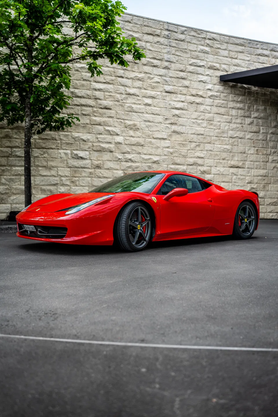 Ferrari 458 Italia neben einer steinernen Bürofassade